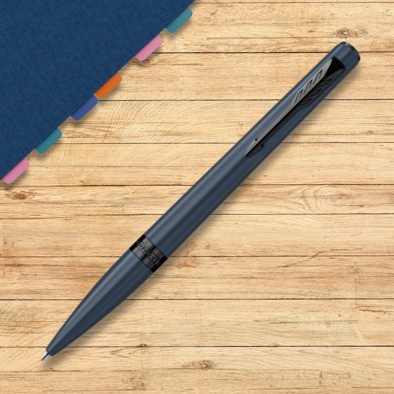 Stylo bille Parker Meridian bleu et noir posé sur un bureau en bois