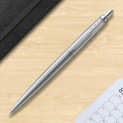 Stylo bille Parker Jotter finition acier photographié sur un bureau en bois.